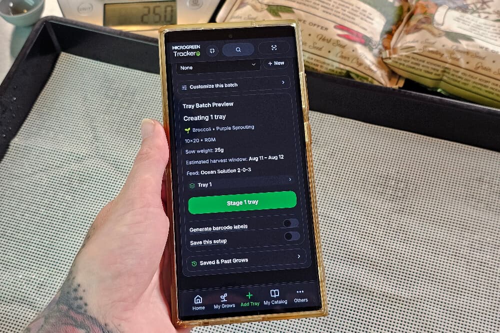 Adding a tray of Purple Sprouting broccoli in the app: the batch preview shows a 25g sow weight, an estimated harvest window, and the feed, above a Stage 1 tray button.